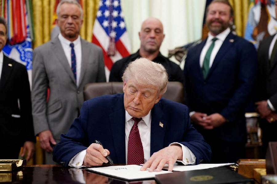US President Donald Trump signs an executive order encouraging more research into ibogaine, next to US Health and Human Services (HHS) Secretary Robert F. Kennedy Jr., Joe Rogan, and Americans for Ibogaine CEO W. Bryan Hubbard, in the Oval Office of the White House in Washington, D.C., April 18, 2026.