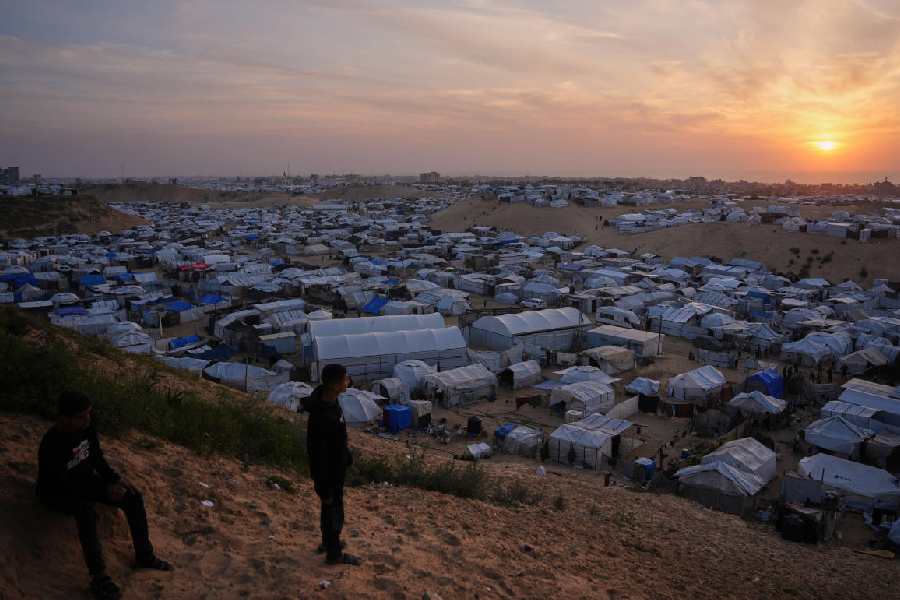 Palestinians youth look on as they stand in an area next to tents at a makeshift camp for displaced people, at sunset in Khan Younis, southern Gaza Strip, Thursday, April 9, 2026.