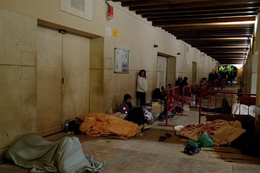 People rest as they wait in a queue in the early morning to obtain a vulnerability certificate to regularise their migration status, at the town hall of Almeria, Spain, April 21, 2026.