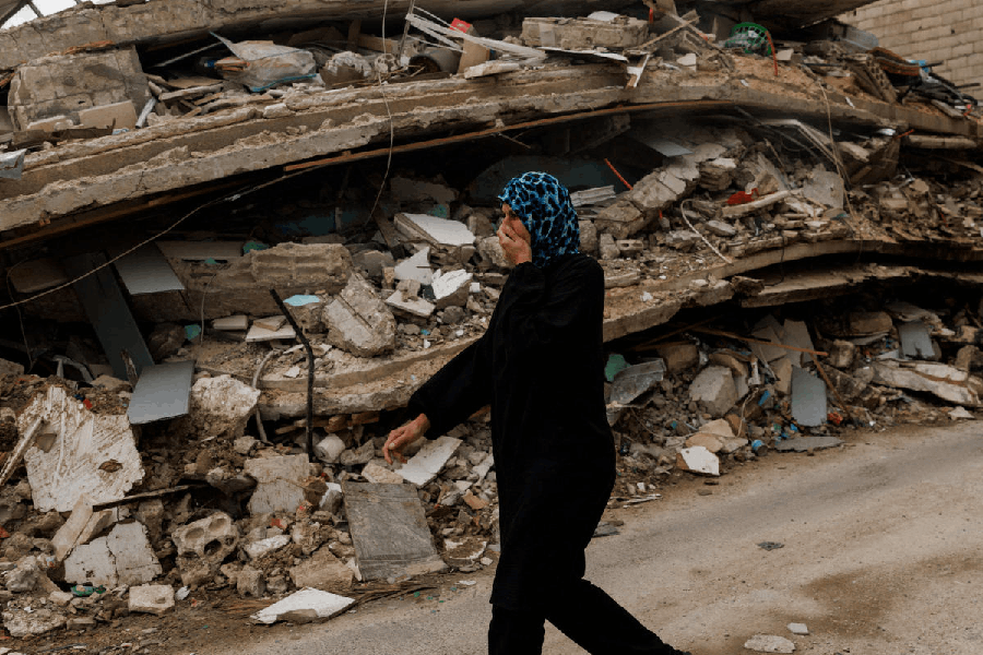 A resident walks while covering her nose to protect against the smell rising from a building containing homes and a restaurant hit by an Israeli strike hours before the ceasefire, amid a 10-day ceasefire between Lebanon and Israel, in Zrarieh, Lebanon, April 19, 2026.