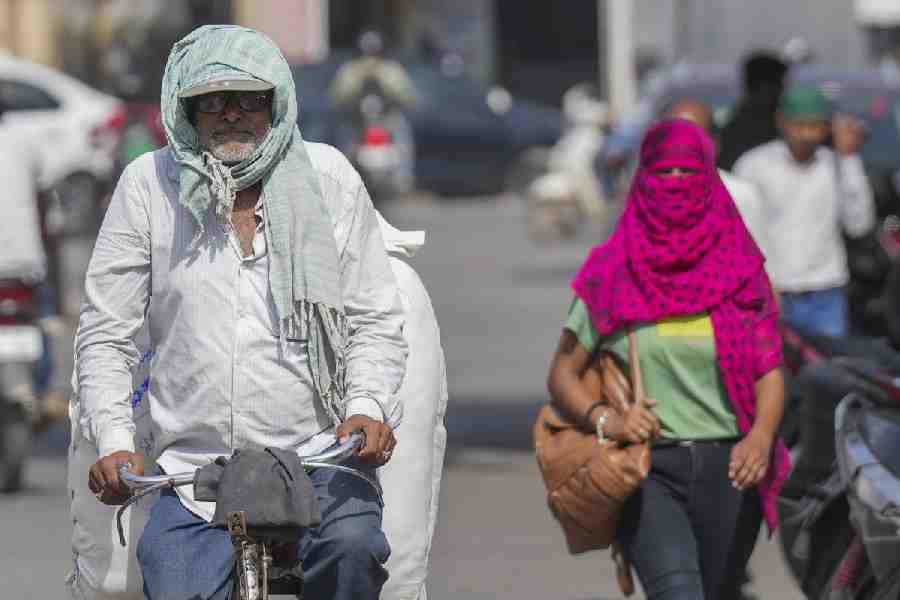 A man covers his head with a scarf amid heatwave on a hot summer day, in Varanasi, Friday, May 31, 2024.