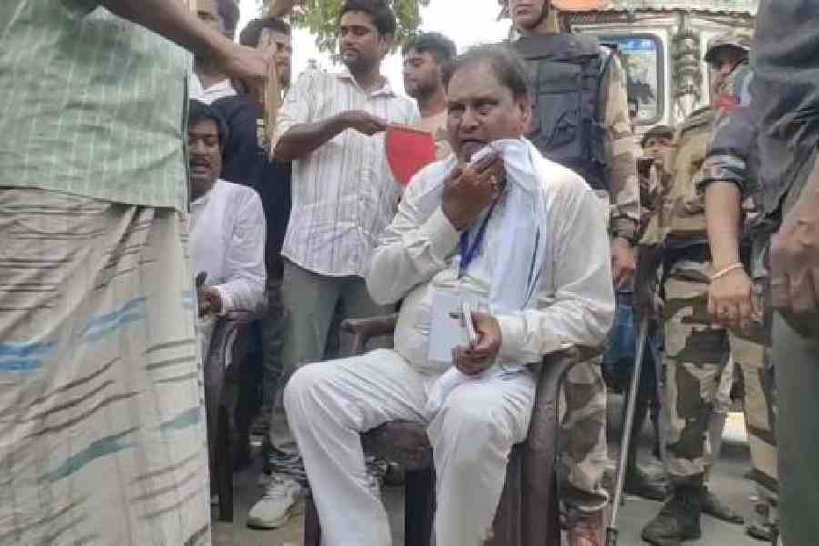 Humayun Kabir sits in a chair in the middle of the road after his car was vandalised on Thursday. Picture by Abdul Halim
