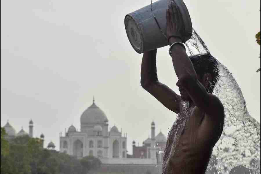 A man pours a bucket of water to beat the heat on a hot summer day, near Taj Mahal in Agra, Uttar Pradesh, Monday, April 20, 2026.