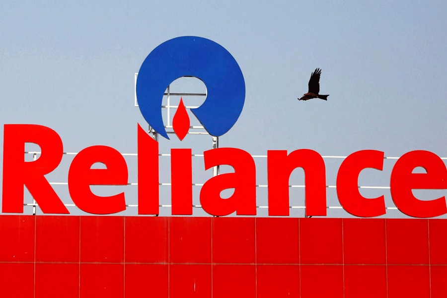 FILE PHOTO: A bird flies past a Reliance Industries logo installed on its mart in Ahmedabad