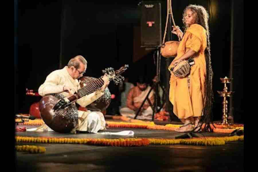 A man plays dhrupad on his sitar and a female singer stands beside him