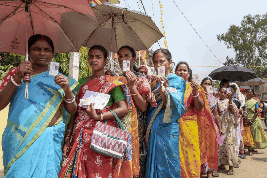 People show their Voter ID cards as they wait in a queue to cast votes on a hot summer day during the first phase of the West Bengal Assembly elections, at a polling station at Bolpur, in Birbhum district, Thursday, April 23, 2026.