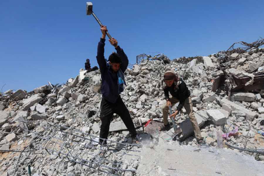 Palestinian workers break up concrete while working on rubble in Khan Younis, southern Gaza Strip, April 19, 2026