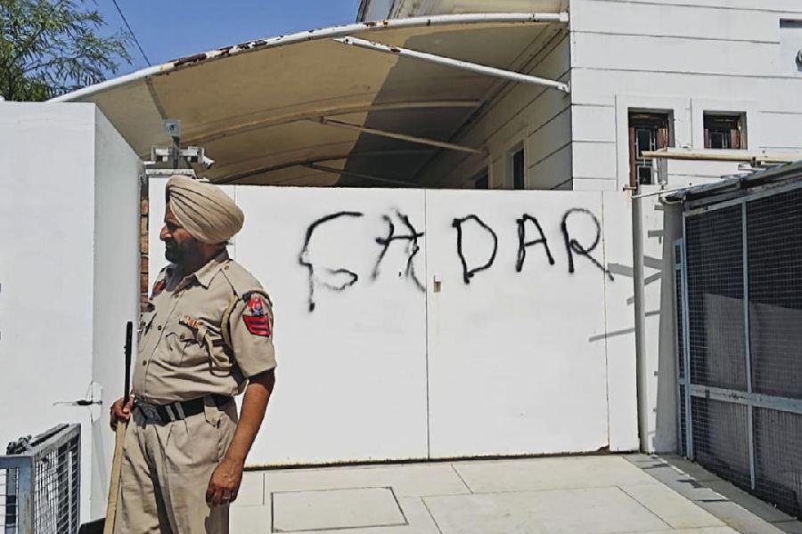 A police official stands guard after AAP workers allegedly wrote 'Gaddar', a traitor, with spray paint on the entrance gate of Rajya Sabha MP Harbhajan Singh