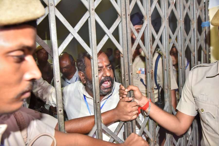 A man in front of close gate which is being held by two police officials.