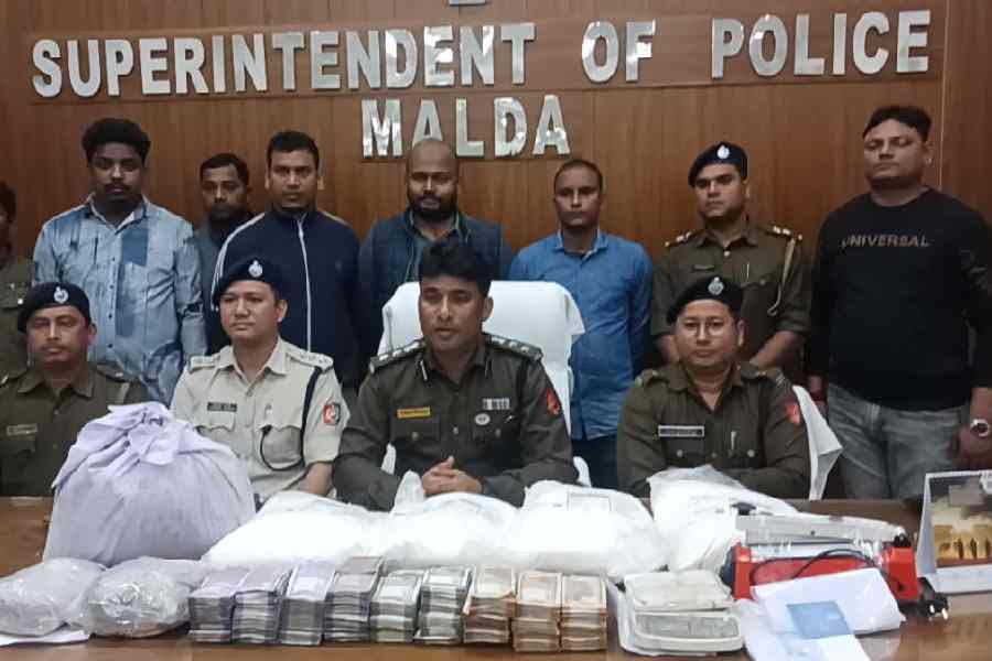 Malda SP Avijit Banerjee, with other police officers, displays the seized narcotics, cash and other items in his office on Tuesday.