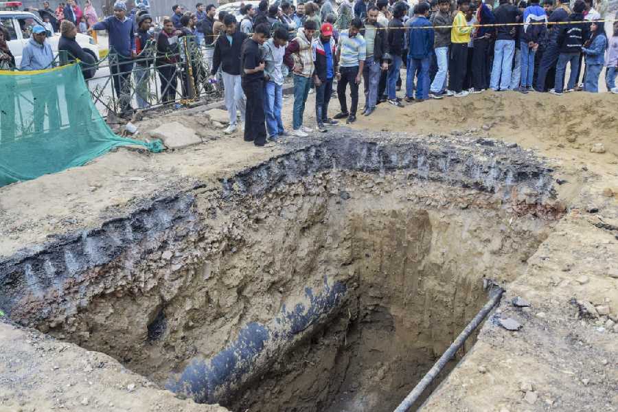 People gather near a 15-foot-deep pit dug for sewage work by the Delhi Jal Board (DJB), where a motorcyclist died after falling, at Janakpuri area, in New Delhi, Friday, Feb. 6, 2026.