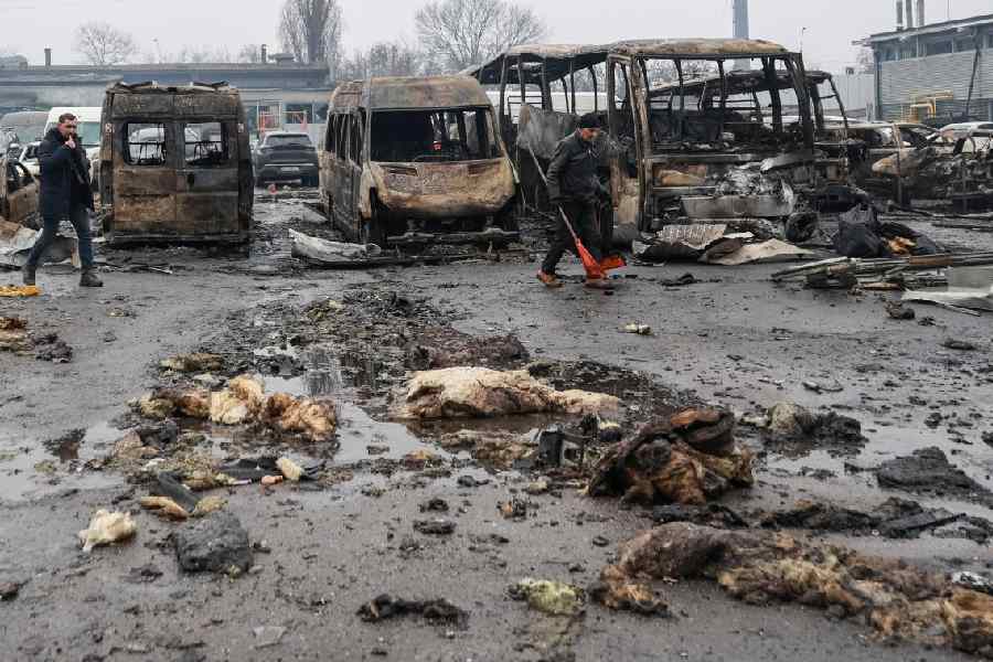 Residents walk near damaged cars at the site of a Russian drone strike, amid Russia's attack on Ukraine