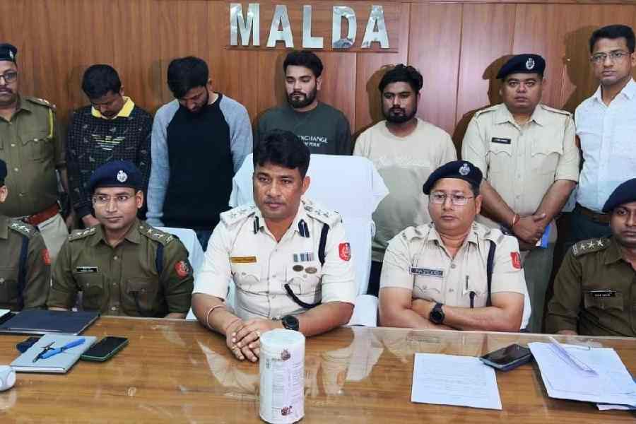 Malda SP Avijit Banerjee with other police officers and the quartet (standing, flanked by cops) nabbed in Goa at his office in Malda on Wednesday.