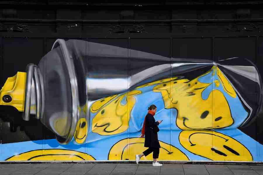 A woman views her phone as she walks past street art on a wall in London, Britain, December 18, 2019.