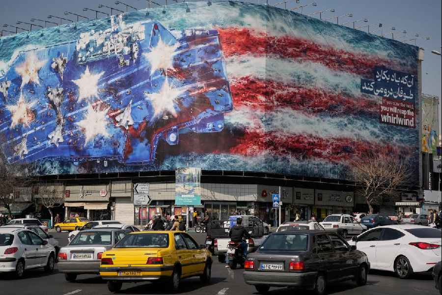 Vehicles pass a billboard of a U.S. aircraft carrier with damaged fighter jets in Tehran, Iran