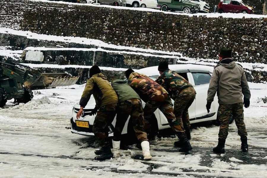 Army personnel push a tourist vehicle stranded on a snowy road in east Sikkim on Sunday.