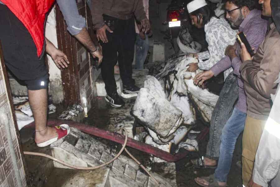Locals inspect the aftermath after a fire broke out at a house, in Meerut