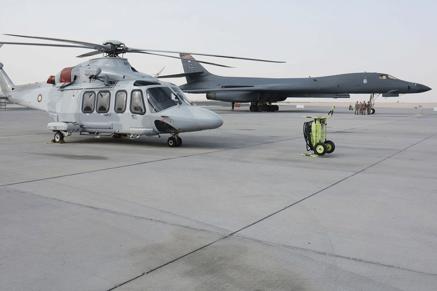 A Qatar Emiri Air Force AW139 and a US Air Force B-1B Lancer on the flight-line at Al Udeid Air Base during 2016