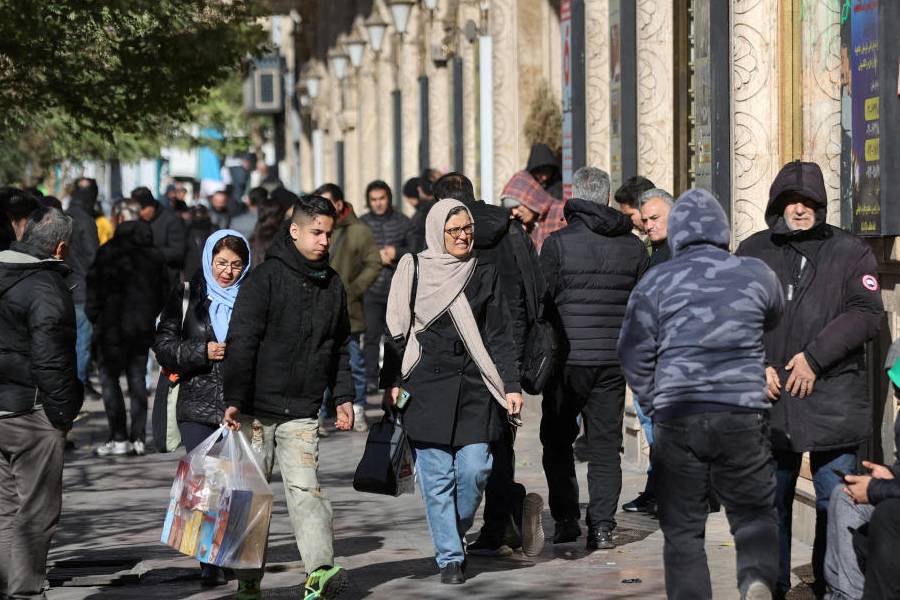 People walk past stores as the value of the Iranian Rial drops, in Tehran, Iran, December 30, 2025.
