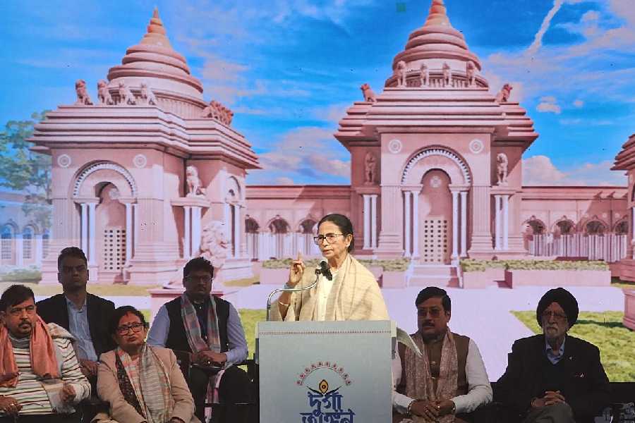 Mamata Banerjee speaks on stage with an artist’s impression of the temple as a backdrop on Monday.