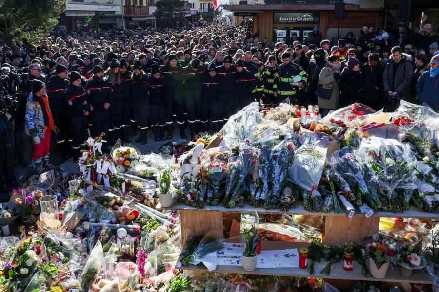 Firefighters and other people mourn at a makeshift memorial outside the "Le Constellation" bar, after a deadly fire and explosion during a New Year's Eve party in the upscale ski resort of Crans-Montana in southwestern Switzerland, January 4, 2026.