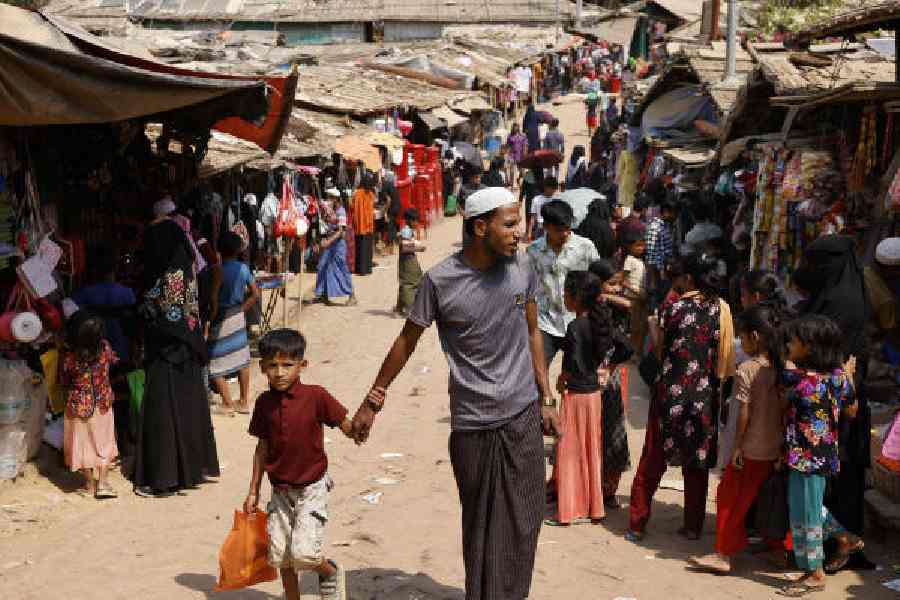 A Rohingya refugee walks with a child in Cox’s Bazar, Bangladesh, in March 2025. 