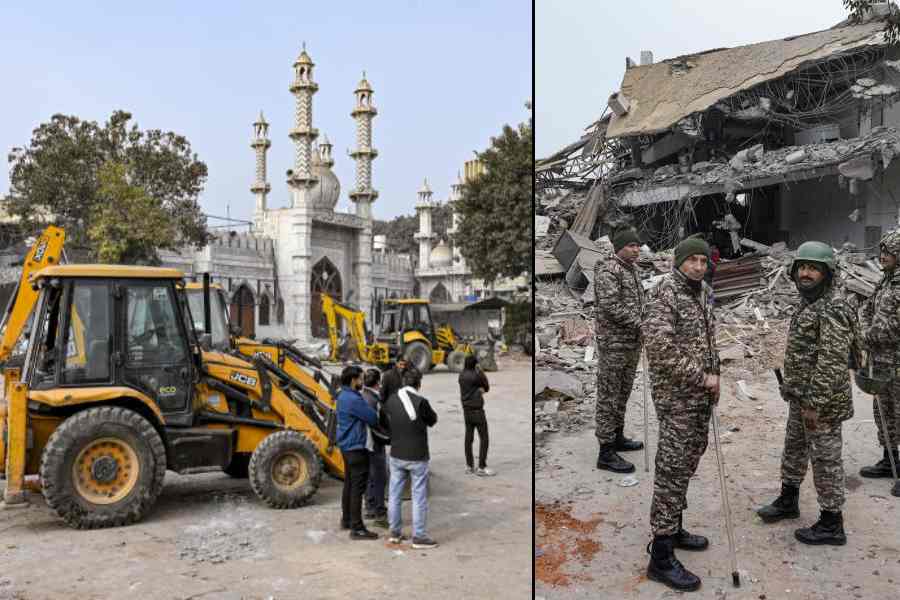 Backhoe loaders deployed during the anti-encroachment drive near the Faiz-e-Elahi Mosque in New Delhi on Wednesday; (right) security personnel keep vigil after violence erupted. 