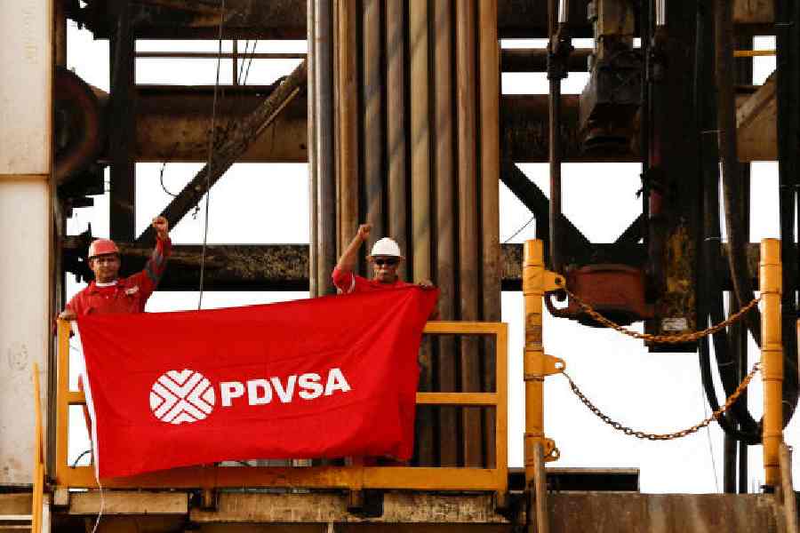 Workers hold a flag with the logo of the state oil company PDVSA on a drilling rig in Anzoategui, Venezuela.