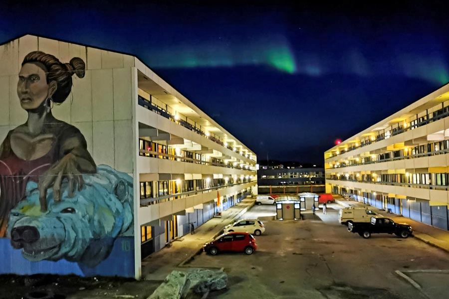 FILE PHOTO: The Aurora Borealis (Northern Lights) is seen behind a building with social housings with a mural in Nuuk, Greenland, September 17, 2021.