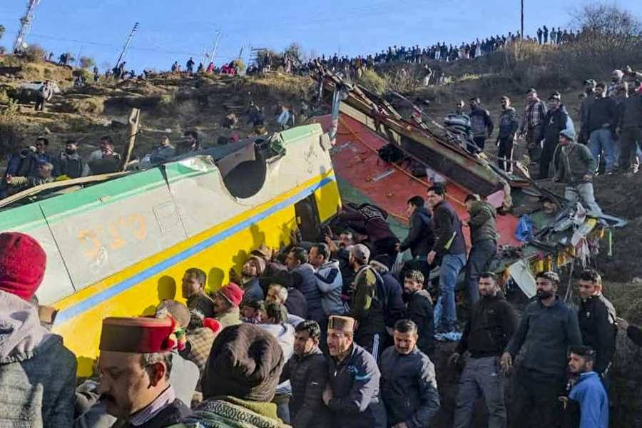 People gather around a private bus that rolled down into a deep gorge, in Sirmaur district, Himachal Pradesh, Friday, Jan. 9, 2026. Eight people died while five others were injured.