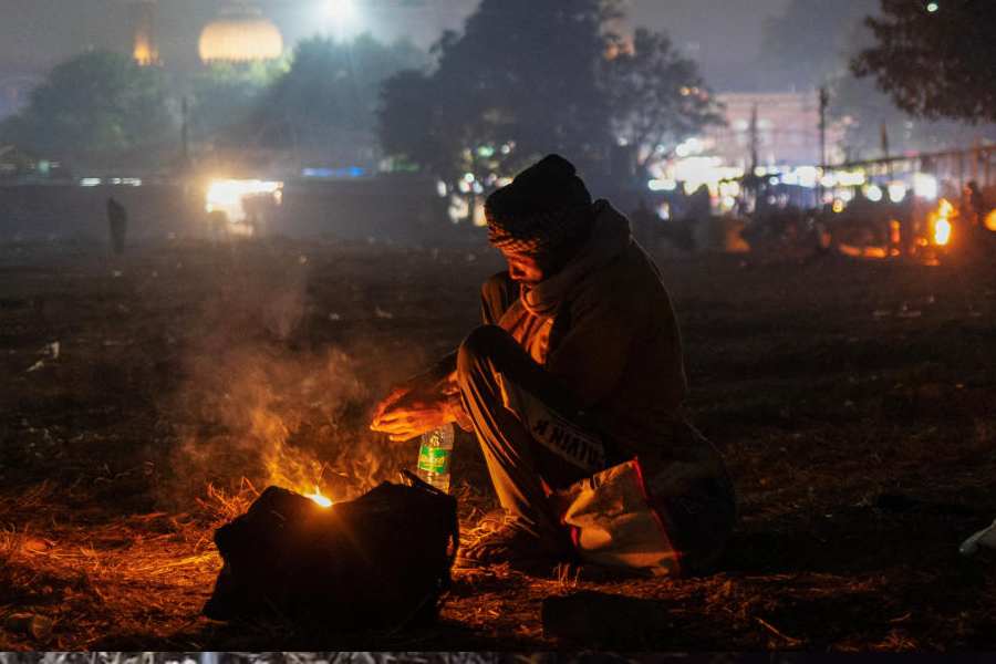 A man warms himself by a fire in front of the Jama Masjid on a cold winter evening in the old quarters of Delhi