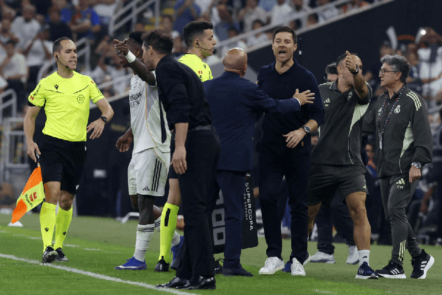 Real Madrid's Vinicius Junior and coach Xabi Alonso react as Atletico Madrid coach Diego Simeone looks on.