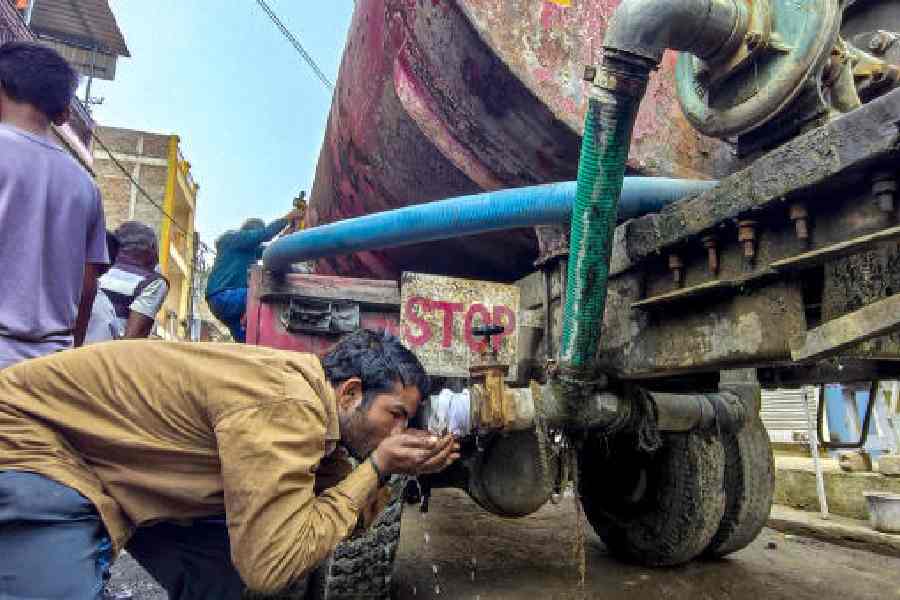 A man drinks water from a tanker in Indore. 