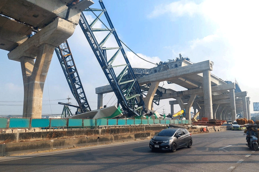Cars drive next to a collapsed crane that crushed two vehicles during construction of an elevated highway in Samut Sakhon province, Thailand, January 15, 2026.