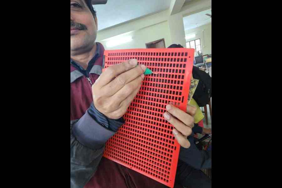 A visually-impaired person shows how Braille is written, at the Workshop for the Blind.
