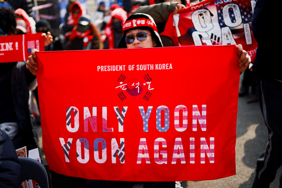 A far-right protester holds a banner with a slogan supporting former South Korean President Yoon Suk Yeol, before a bus carrying him arrives for a first court verdict in a case including obstruction of arrest, linked to his martial law declaration, at a court in Seoul, South Korea, January 16, 2026.