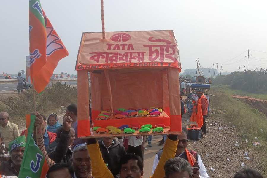 BJP supporters walk to Modi’s rally with a handmade model of a Tata car factory in Singur on Sunday.