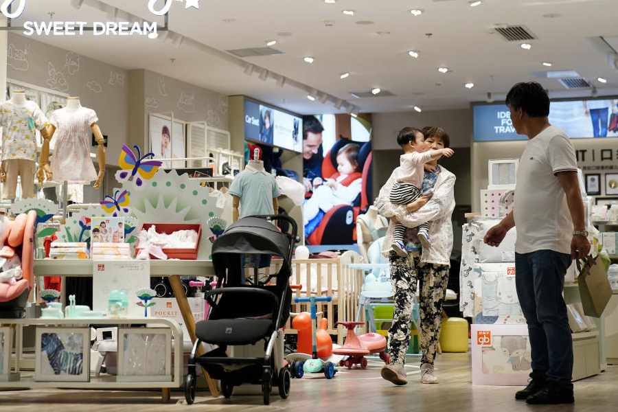 An adult holding a baby walks at a store selling baby products in Shanghai, China