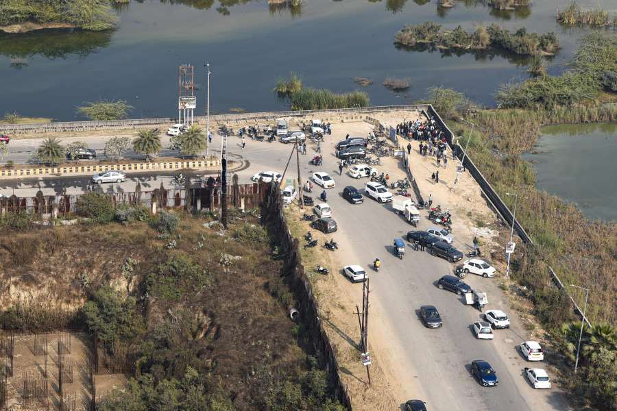 People gather near a water-filled pit at a construction site following the death of a 27-year-old engineer who drowned, in Noida, Monday, Jan. 19, 2026.