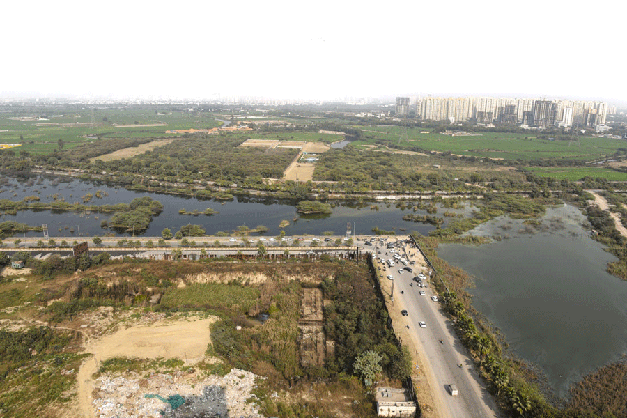 People gather near a water-filled pit at a construction site following the death of a 27-year-old engineer who drowned, in Noida, Monday, Jan. 19, 2026.