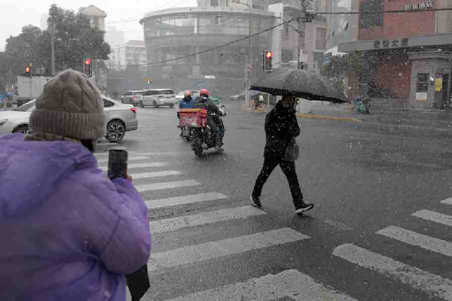 A pedestrian holding an umbrella crosses an intersection amid snowfall in Shanghai, China January 20, 2026.