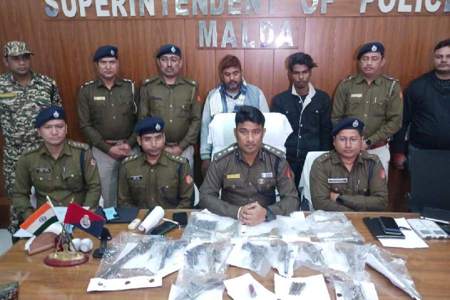 Senior police officers with the arrested duo and the seized firearms at the superintendent of police’s office in Malda on Tuesday. 