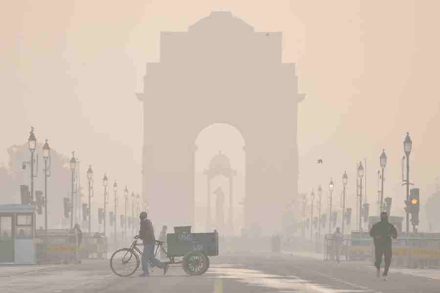 The India Gate shrouded in a layer of smog as people make their way during a cold winter morning, at Kartavya Path, in New Delhi, Wednesday, Dec. 24, 2025.