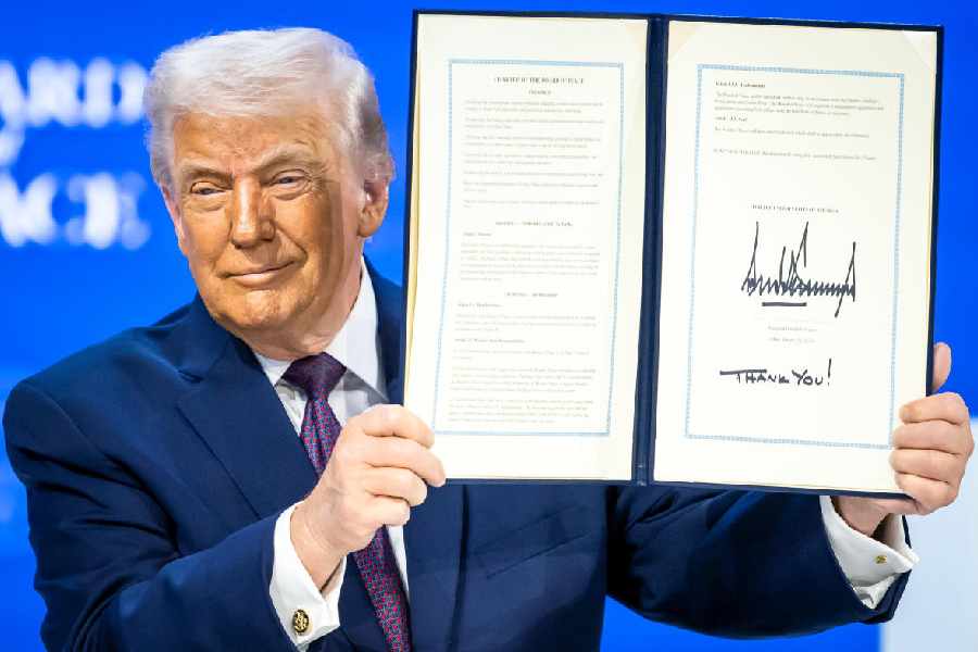 President Donald Trump, center, holds up a signed Board of Peace charter during the Annual Meeting of the World Economic Forum in Davos, Switzerland