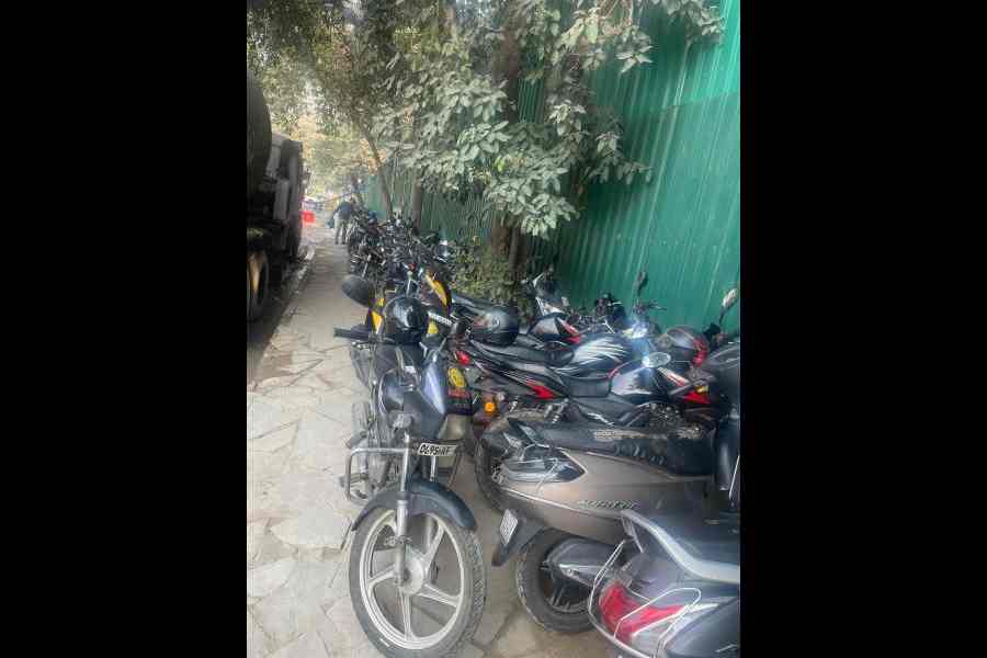 A row of bikes parked on a pavement near an under-construction building of Kartavya Bhavan