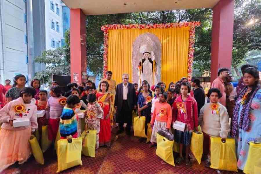 Children from The Refuge in front of the idol with their gifts  and Dr Sukumar Mukherjee
