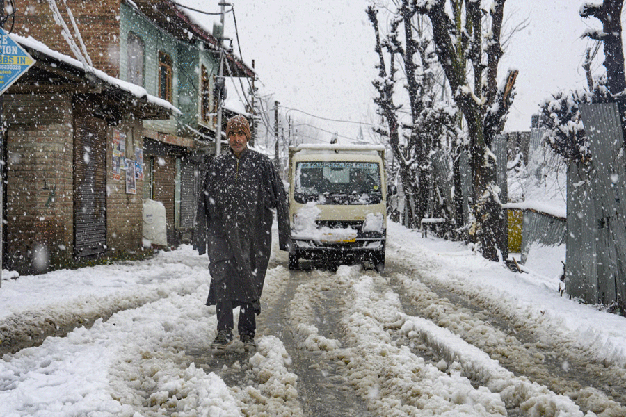A man walks along a snow-covered street amid snowfall on the city's outskirts, in Srinagar, Jammu and Kashmir, Friday, Jan. 23, 2026.