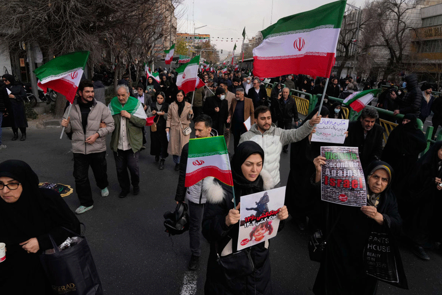People carry Iranian flags and pro-government placards during a funeral ceremony for a group of security forces, who were killed during anti-government protests, in Tehran, Iran, Wednesday, Jan. 14, 2026.