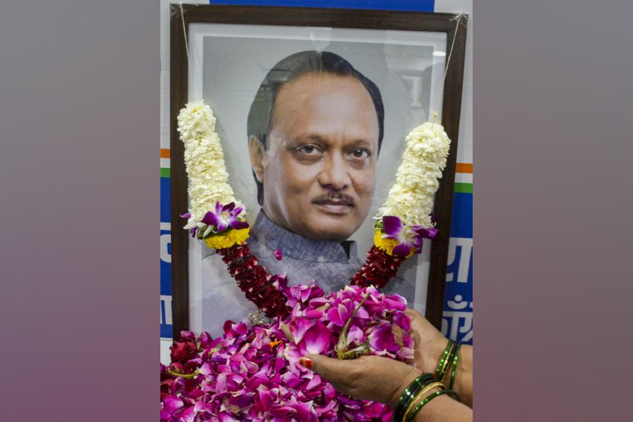 A worker of the NCP's Ajit Pawar faction pays floral tribute to a photograph of the late Maharashtra Deputy Chief Minister Ajit Pawar at the party office in Thane, Maharashtra, Wednesday, Jan. 28, 2026.