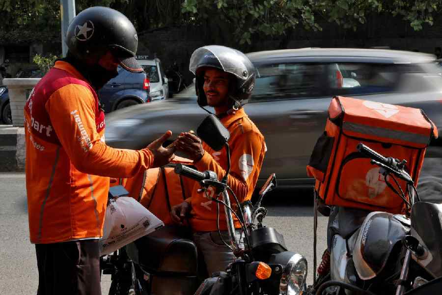 Gig workers prepare to deliver orders outside Swiggy's grocery warehouse at a market area in New Delhi, India, May 6, 2024.